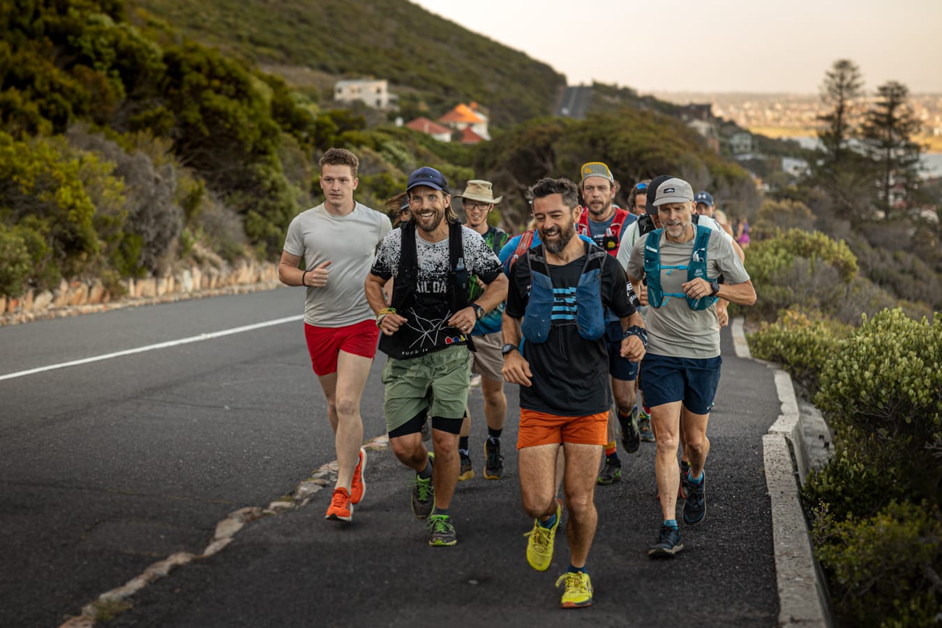 Happy group of runners on paved road with coastal vegetation showing joy and camaraderie