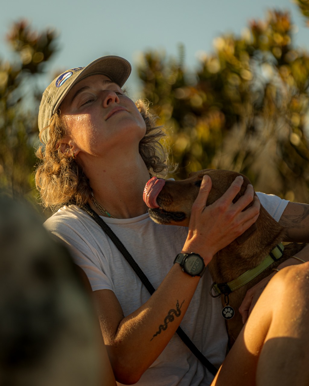 Female runner in golden light lovingly cuddling brown dog