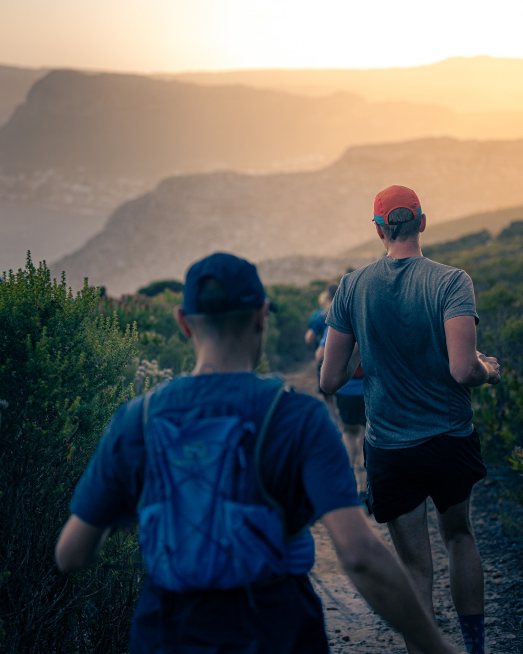Trail runners from behind during golden hour with mountain silhouettes