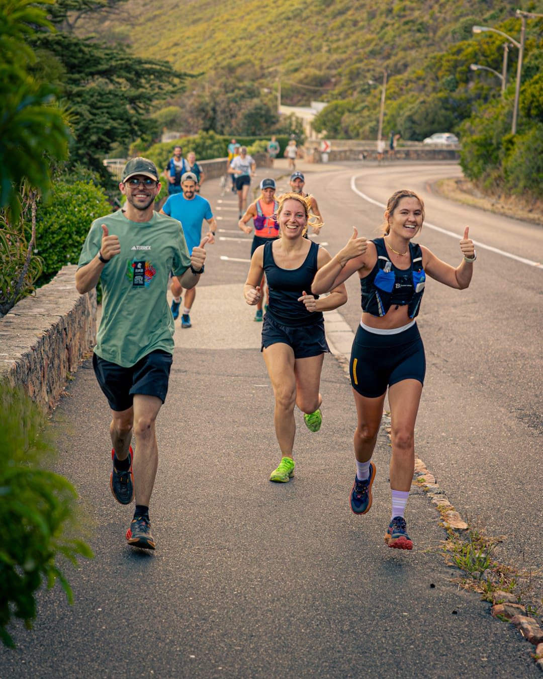 Group of enthusiastic trail runners giving thumbs up on road